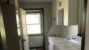 Eine Küche mit großem Fenster, weißen Schränken und einem eingebauten Backofen.