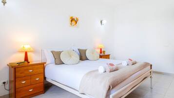 A neatly made bed with a white and beige duvet, two bedside tables with lamps, and a wall-mounted light fixture.