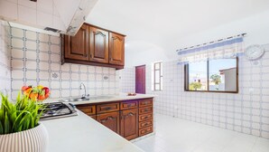 A kitchen with wooden cabinets, a marble countertop, and a window with a view.