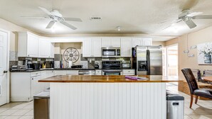 A modern kitchen with white cabinets, a wooden island, stainless steel appliances, and ceiling fans. - Pet-Friendly Lilburn Duplex w/ Patio & Grills! (Lilburn)