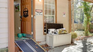 A house entrance with a wooden door, a sign warning of a fox, and a small porch area with a planter and a magazine rack. - Pet-Friendly Lilburn Duplex w/ Patio & Grills! (Lilburn)