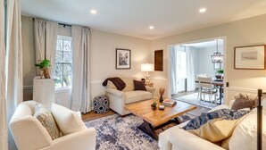 A living room with a sofa, armchairs, a coffee table, and a dining area in the background. - Peaceful Queenstown Home w/ Deck & Grill! (Queenstown)