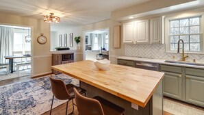A kitchen with a wooden island, white cabinets, and a herringbone backsplash. - Peaceful Queenstown Home w/ Deck & Grill! (Queenstown)