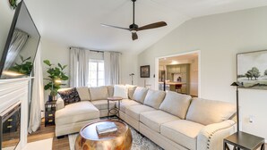 A living room with a large L-shaped beige sofa, a round coffee table, a ceiling fan, and a fireplace. - Peaceful Queenstown Home w/ Deck & Grill! (Queenstown)