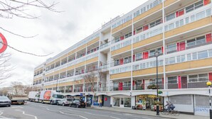A multi-story building with balconies, a street in front, and a parked truck. - Delightful & Well-located 2BD Flat Central Pimlico (London)