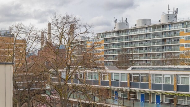A multi-story residential building with balconies, a paved courtyard, and a tree with pink blossoms. - Delightful & Well-located 2BD Flat Central Pimlico (London)