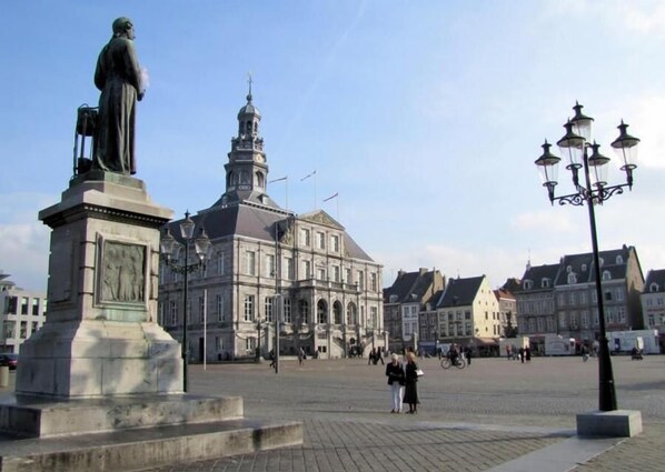 A historic building with a prominent tower and a statue in the foreground.