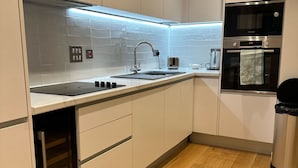 Eine moderne Küche mit weißen Schränken, einer Edelstahlspüle, einem Backofen von Bosch und einem eingebauten Geschirrspüler.
