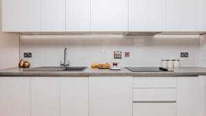 Eine moderne Küche mit weißen Schränken, einer Edelstahlspüle und einer Arbeitsplatte mit Frühstücksgebäck.