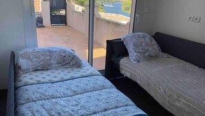 A room with two beds, one with a patterned bedspread and the other with a plain one. - Joli Mas T3 vue Mer. Animaux de Compagnie Acceptés ! (Istres)