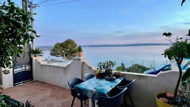 A terrace with a table and chairs, overlooking a body of water. - Joli Mas T3 vue Mer. Animaux de Compagnie Acceptés ! (Istres)