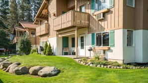 Un edificio in legno a più piani con balconi, un prato curato e un giardino roccioso.