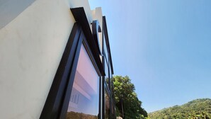 Ein modernes Gebäude mit einem großen Fenster und Blick auf eine Hügellandschaft.