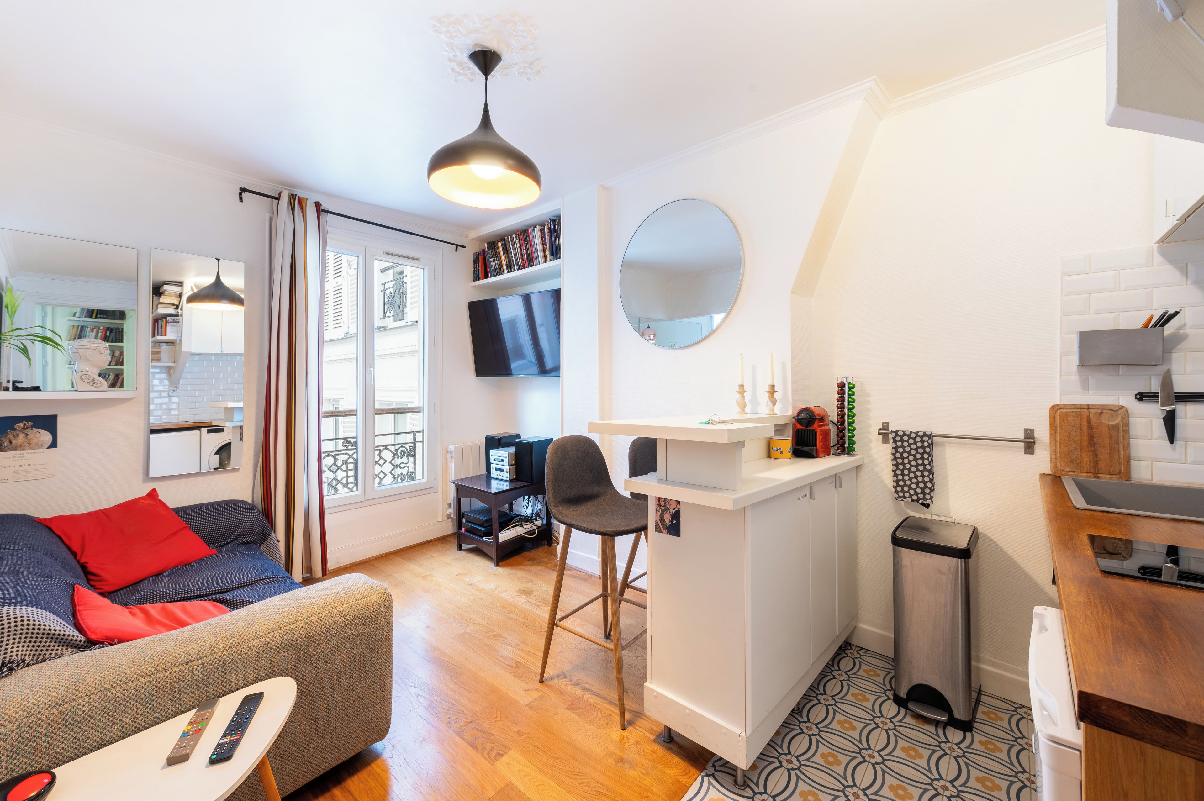 A compact living space with a sofa, a dining area, a kitchen, and a small bar area.