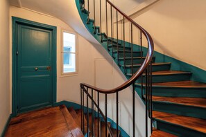 A staircase with wooden steps and a metal handrail, leading to a door with a window.