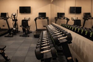 Une salle de sport équipée de matériel d’exercice, notamment des tapis de course, des vélos d’appartement et des haltères.