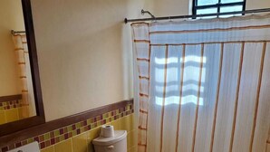 Un baño con inodoro, lavamanos y cortina de ducha.
