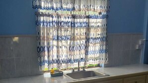 Una cocina con un lavamanos, armarios y una ventana con diseño.