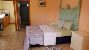 Un dormitorio con cama, mesita de noche, cómoda y puerta que da a otra habitación.