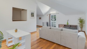A modern living room with a white sofa, a small white table, and a wooden floor. - Encanto Santa Cruz (Santa Cruz)