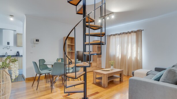 A modern living room with a spiral staircase, a sofa, a dining table, and a kitchen area. - Encanto Santa Cruz (Santa Cruz)