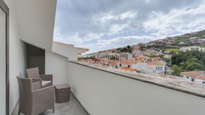 A balcony with wicker furniture, a view of a hillside town with red-roofed buildings. - Encanto Santa Cruz (Santa Cruz)