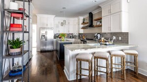 A modern kitchen with white cabinetry, a central island with bar stools, and a built-in oven.