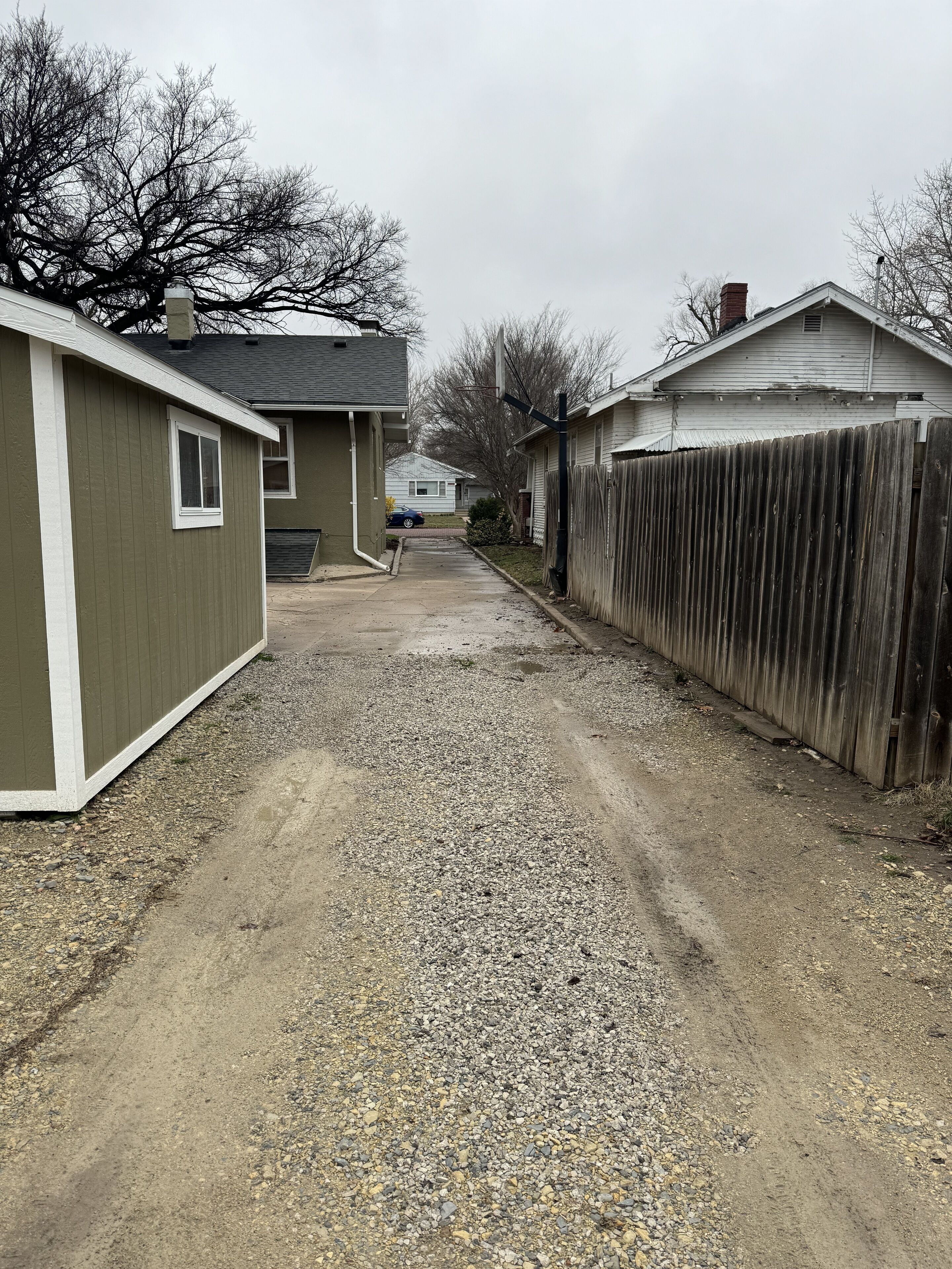 Une allée menant à une maison, avec une clôture en bois et un garage.