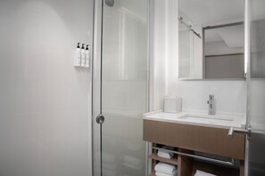 Une salle de bain moderne avec une douche à parois de verre, un lavabo blanc et un miroir au-dessus.