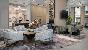Un hall d’hôtel moderne avec un comptoir d’accueil, un espace salon et de grandes fenêtres.