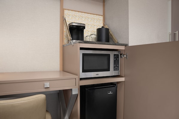 Una kitchenette equipada con microondas, cafetera y refrigerador.