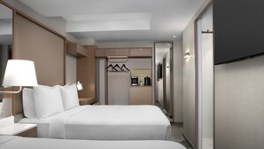 Une chambre d’hôtel moderne équipée de deux lits, d’un bureau, d’une lampe, d’une télévision et d’une kitchenette.