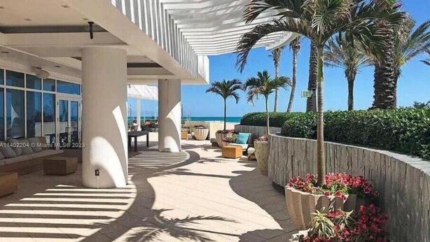 A modern outdoor area with a curved pathway, seating arrangements, and a view of the ocean.
