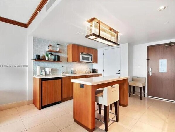 Una cocina moderna con armarios de madera, una isla central y una lámpara colgante.
