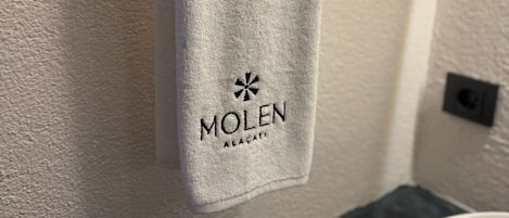 A towel hanging on a hook with the logo "MOLEN" and the text "AEÇAT" on it.
