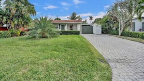 A modern house with a paved driveway, surrounded by well-maintained lawns and tropical plants. - Work & Play Retreat. Private Office. 1GB Internet (Oakland Park)