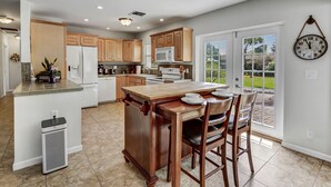 A spacious kitchen with wooden cabinets, a central island, and a dining area with chairs. - Work & Play Retreat. Private Office. 1GB Internet (Oakland Park)