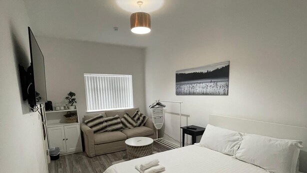 A modern bedroom with a large bed, a sofa, a TV, and a painting on the wall. - Citybreaks Rooms (Liverpool)