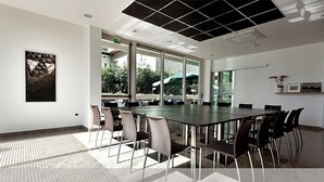 A conference room with a long table and chairs, large windows, and a ceiling with a grid pattern. - Cristallo Rimini (Rimini)