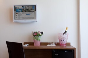 A hotel desk with a computer monitor displaying a hotel website, a vase with flowers, and a champagne glass with ice. - Cristallo Rimini (Rimini)