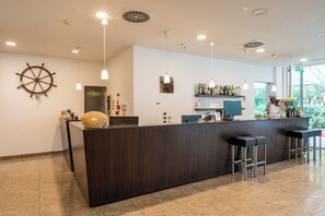 Zona de bar moderna amb un taulell de fusta, llums penjants i una decoració amb timó de vaixell.