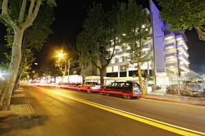 A modern hotel with multiple floors, a well-lit facade, and a tree-lined street. - Cristallo Rimini (Rimini)
