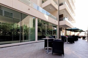 An outdoor patio with modern furniture, large windows, and a view of greenery. - Cristallo Rimini (Rimini)