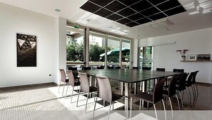 Ein Konferenzraum mit langem Tisch und Stühlen, großen Fenstern und einer Decke mit Rastermuster.