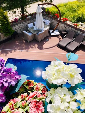 An outdoor patio with a pool, lounge chairs, and a table with chairs. - VİA PERLA BUTİK OTEL (Cesme)