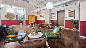 A spacious lounge area with leather chairs, a round table, and potted plants. - Modern Dallas Retreat with Pool & In-Unit Laundry (Dallas)