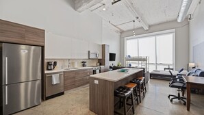 A modern kitchen with stainless steel appliances, a central island with stools, and a large window providing natural light. - Modern Dallas Retreat with Pool & In-Unit Laundry (Dallas)