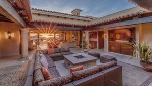 Un amplio patio al aire libre con un sofá grande, una mesa de centro de piedra y una planta en maceta.