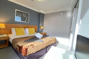 Ein Hotelzimmer mit einem großen Bett, zwei Nachttischen, einem Fenster mit Blick und einem gerahmten Bild an der Wand.