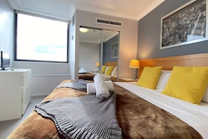 Una habitación de hotel con una cama grande, un escritorio, un espejo y una ventana.